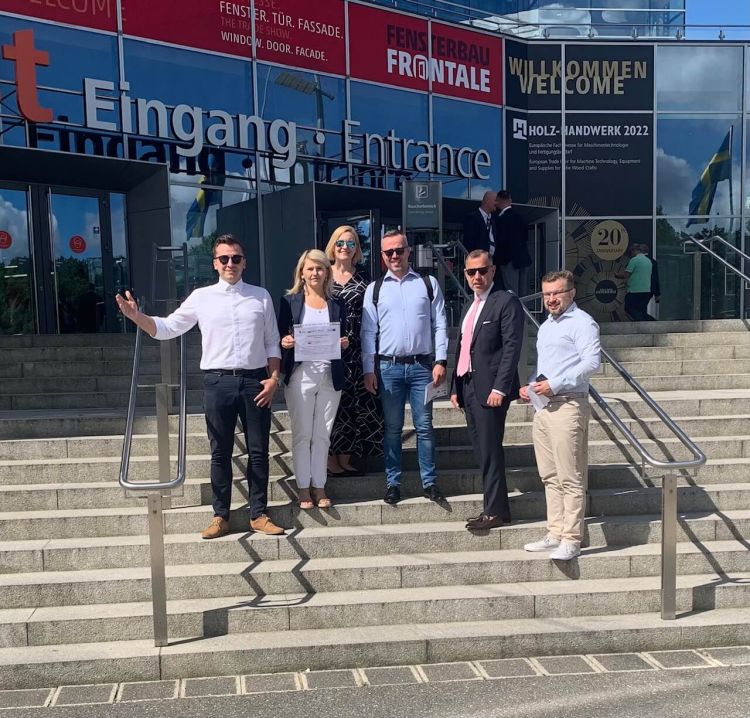 ludzie pozujący przed budynkiem w którym odbyły się targi