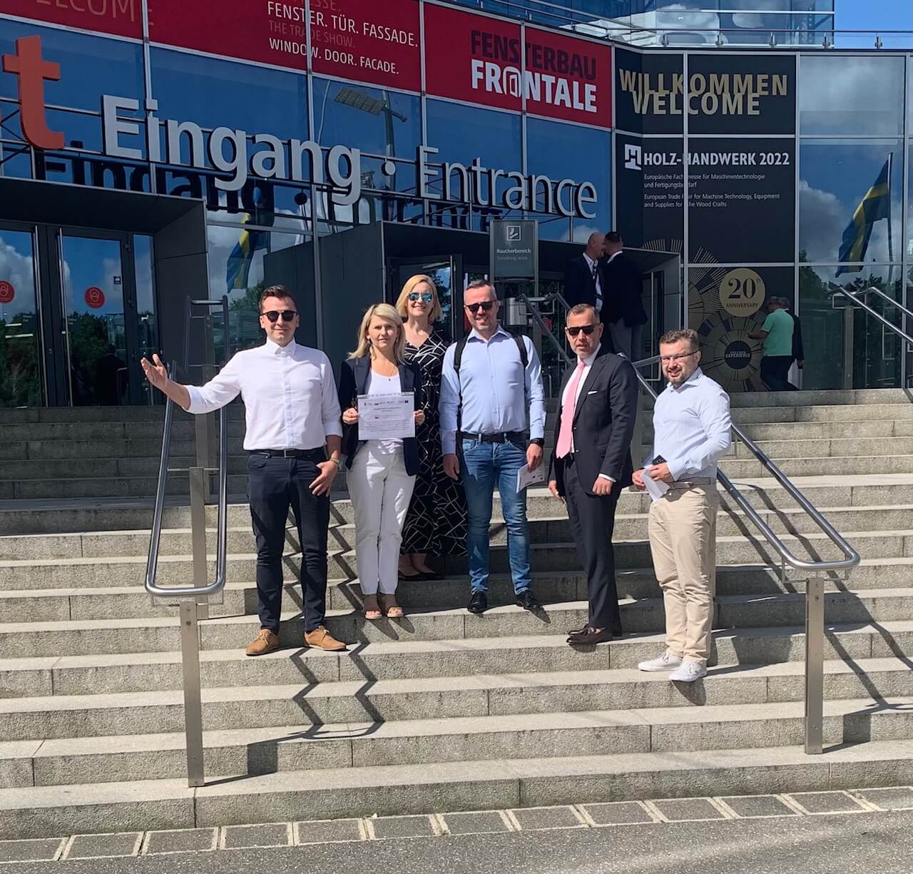 ludzie pozujący przed budynkiem w którym odbyły się targi