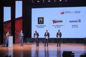 Mężczyźni stojący na scenie z nagrodami